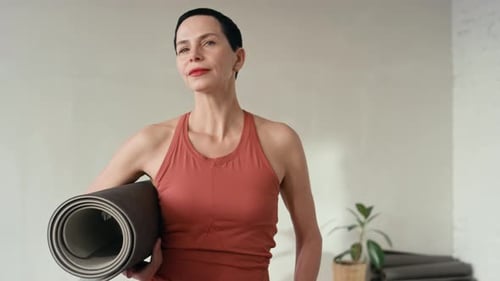 Portrait of Confident Middle-Aged Woman Holding Yoga Mat in Fitness Studio
