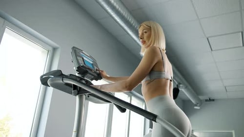 Woman walking on climbing machine in a fitness club, gym, cardio workout