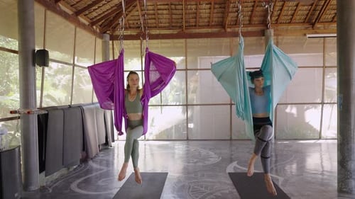 Women Practicing Yoga in Hammocks in Tropical Studio
