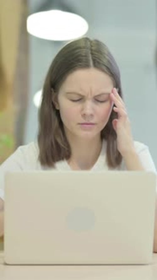 Woman with Headache Massaging Temples at Desk
