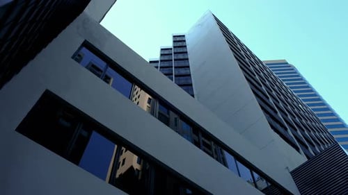 The low angle panning view of the city skyline buildings and blue sky.