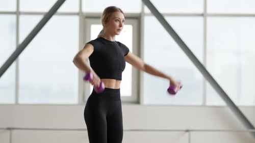Beautiful Healthy Female Athlete Lifting Dumbbells in Gym