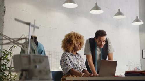 Tailor Discussing Fashion Design on Laptop with Female Coworker