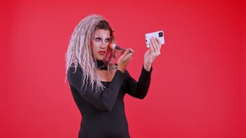 Person Applies Makeup with Phone on Red Background
