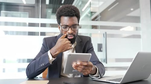 Focused Young Adult Using Tablet at Office Desk