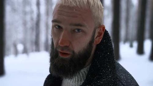 Einsamer Mann, der durch den Schnee läuft. Medien. Junger Mann mit Schnee auf der Jacke fühlt sich allein und isoliert