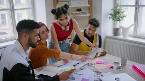 Vue de face d'un groupe de jeunes rédacteurs au bureau, travaillant ensemble sur un projet.