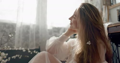 Retrato de una mujer elegante con un vestido de novia vintage sentada en el suelo posando en casa con estilo