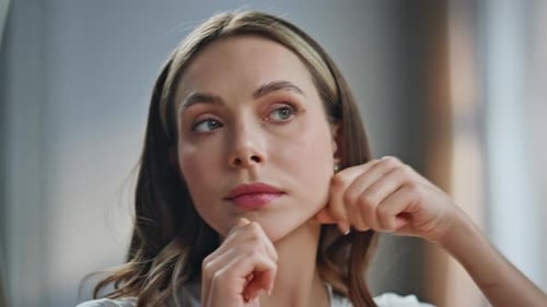 Young Woman Styles Face in Bathroom Mirror