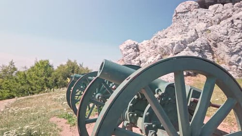 Artillery cannons in line on historical battleground memorial pan down