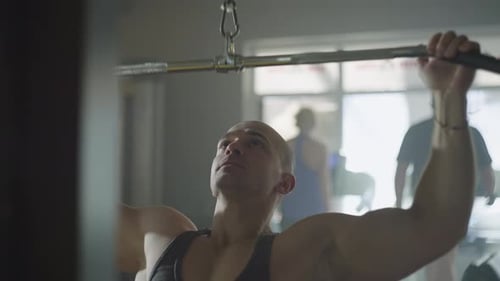 Handsome Muscular Caucasian Athlete Working Out on Exercise Machine in Gym
