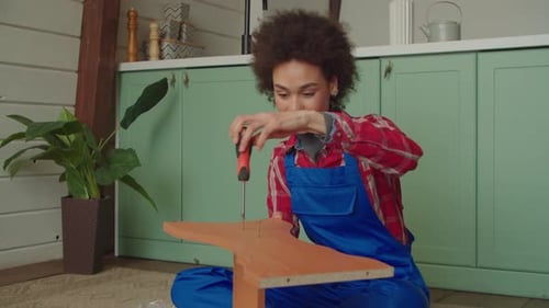Lovely African American Woman Assembling DIY Furniture with Screwdriver at Home