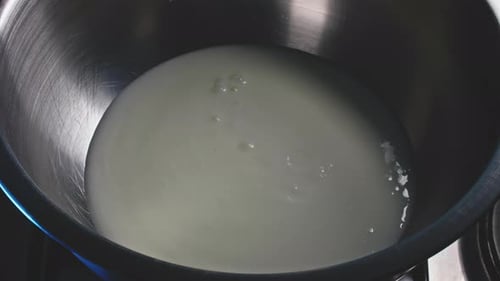 A closeup overhead shot of a bowl where a white dressing is poured in and a red sauce is carefully a