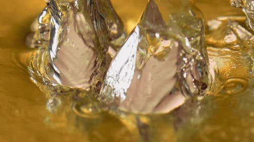 Boiling liquid gold with ice cubes. Elegant slow-motion footage of a high-end drink in extreme close