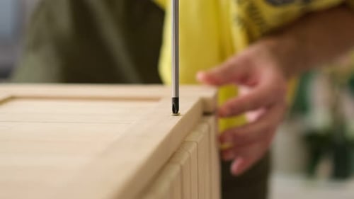 Closeup Man Hand Using Manual Screwdriver and Screwing Screw in Board