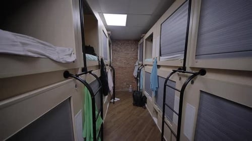 Des rangées de lits à capsules dans un dortoir d'auberge moderne avec mur de briques