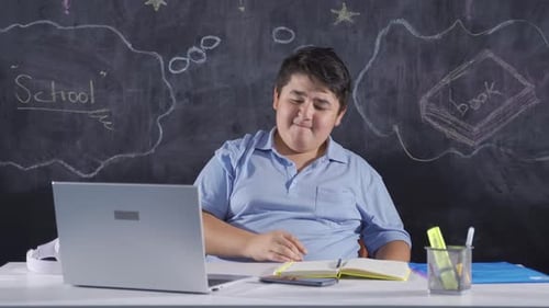 Overworked Student Studying at Desk with Laptop