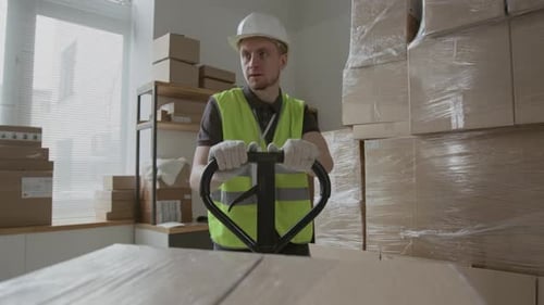Man Moving Packages with Pallet Jack in Warehouse