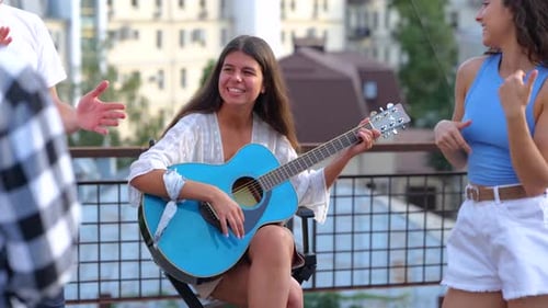 Young Adults Jamming on Rooftop with Guitar