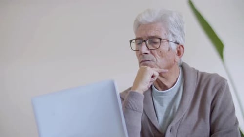 Senior Man Concentrating on Laptop Indoors