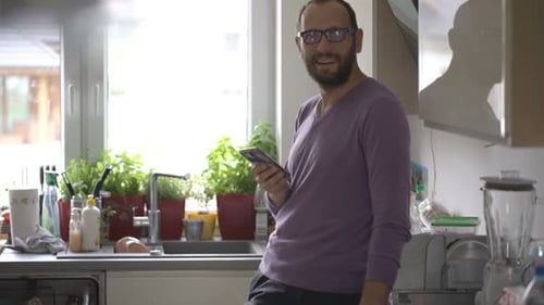 Man Using Smartphone in Bright Kitchen Environment