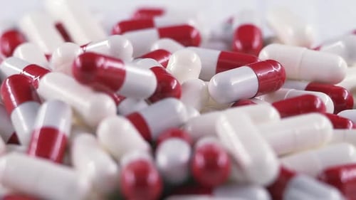 Capsule on a White Background Filled with Medicine is in a Chaotic Order Pills Fall on the Table