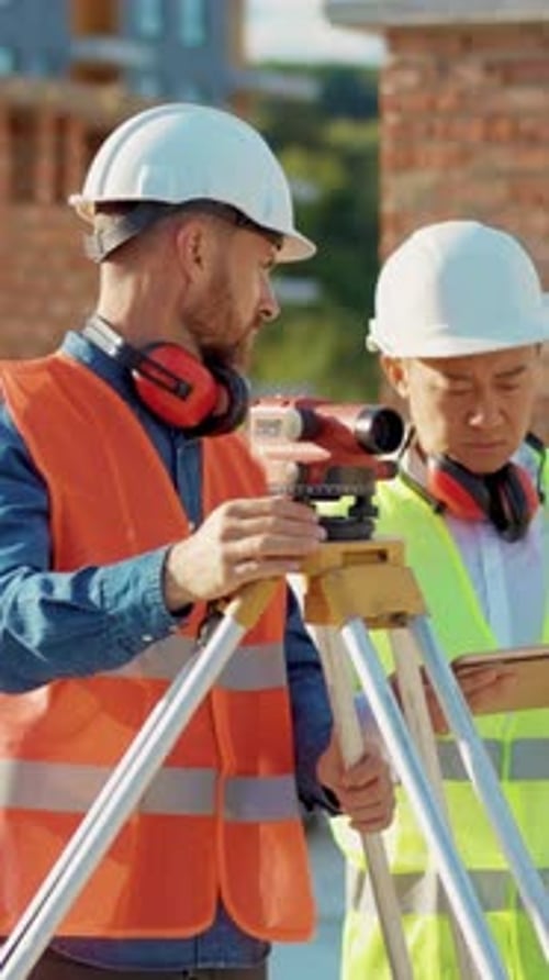 Construction Workers Surveying Building Site Using Technology