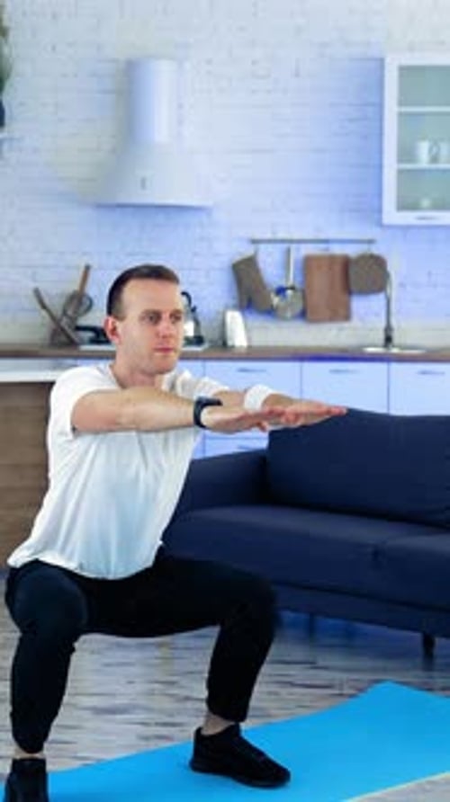 Man Doing Squats on Yoga Mat Indoors
