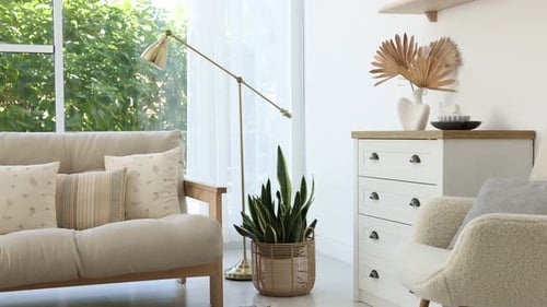 Beautiful living room with lamp, stylish furniture and plant, interior design. Camera moving left