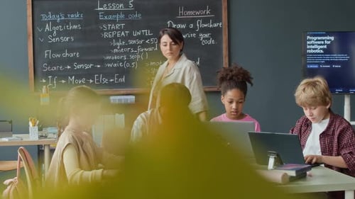 Des enfants diversifiés apprennent la programmation avec un enseignant dans un cours de robotique