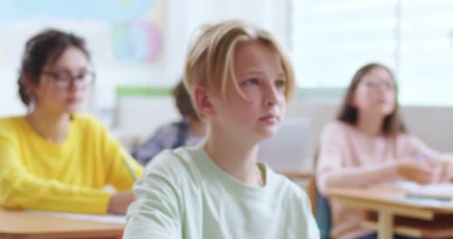 Boy Sits at Desk in Classroom