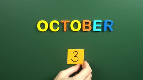 Hand sticking a sticker 3 October calendar day on school board. 3 date of October. Third day