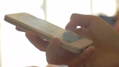 Hand scrolls through a cellphone indoors