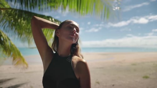 Woman Standing on Beach Next to Palm Tree