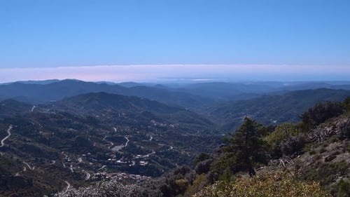 Aerial drone view over the mountain peak revealing villages in the distance
