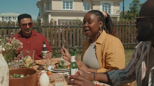 Friends Enjoying Outdoor Meal in Sunny Backyard