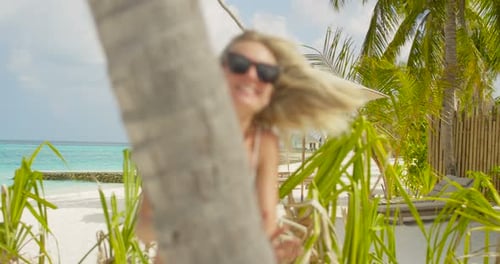 Linda mulher brincalhona se esconde atrás da palmeira. Férias românticas em um local quente e exótico N