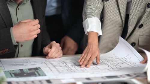 Team Analyzing Architectural Blueprint in the Office
