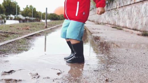 Child Jumping in a Puddle Wearing Black Boots