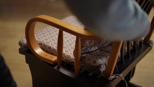 Person Disassembling a Cushioned Wooden Chair