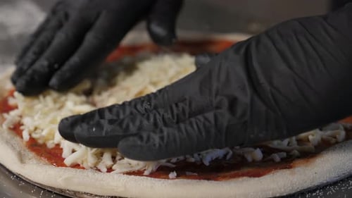 A Chef Sprinkles Grated Cheese and Tomato Sauce on Pizza in a Pizzeria Kitchen
