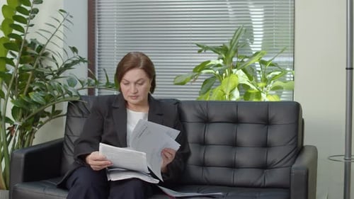 Woman Reviewing Documents on Office Sofa