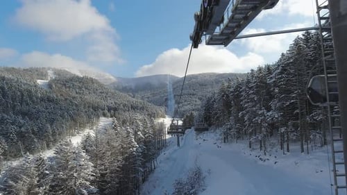 Riding on Ski Lift Between Snow Covered Pinetrees in the Morning POV Shot Winter Vacation Concept