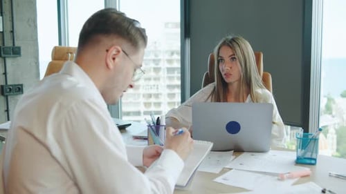 Two Professionals Engaged in a Discussion at a Modern Office During a Work Meeting Focusing on