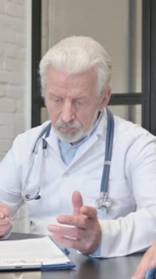 Senior Doctor Taking Notes During Patient Consultation