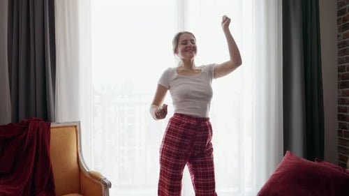 Young Woman Dancing in Pajamas by the Window