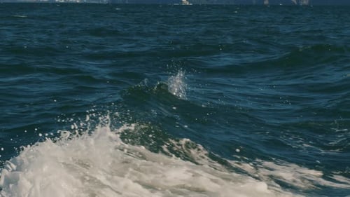 Turbulentes Wasser und weiße Schaumspritzer vom Bootsmotor vor dem Hintergrund blauer Meereswellen