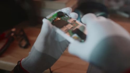 Unbekannter Techniker untersucht die Hauptplatine des Telefons mit einer Lupe