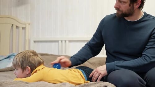 Father Using a Spiky Massage Ball for Son to Relieve Muscle Tension Aid Recovery After Intense