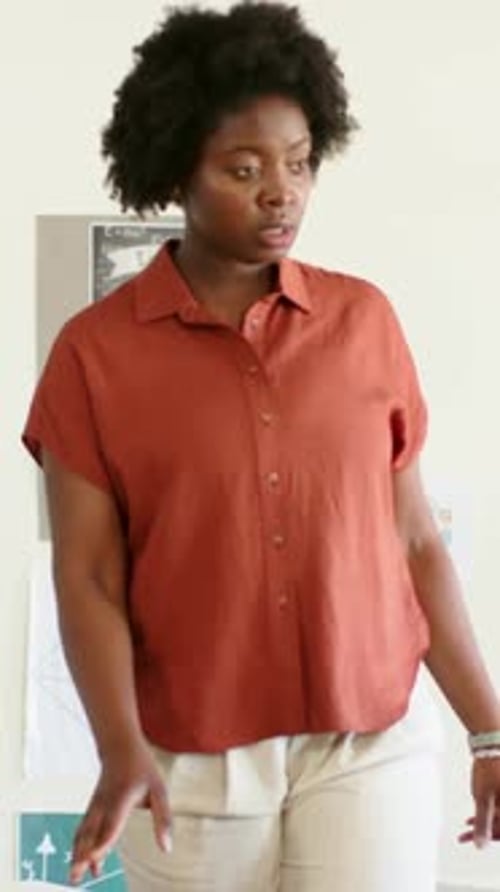 Vertical video: Entering classroom, teacher in rust top and tan pants leaning on desks teaching